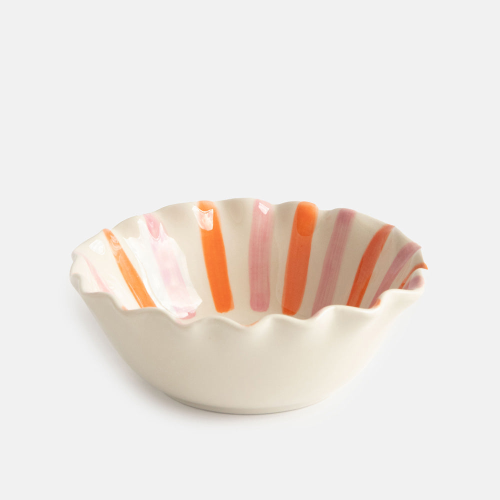 scalloped edge glazed stoneware cereal bowl with pink and orange stripes and black bow design inside and white on the outside