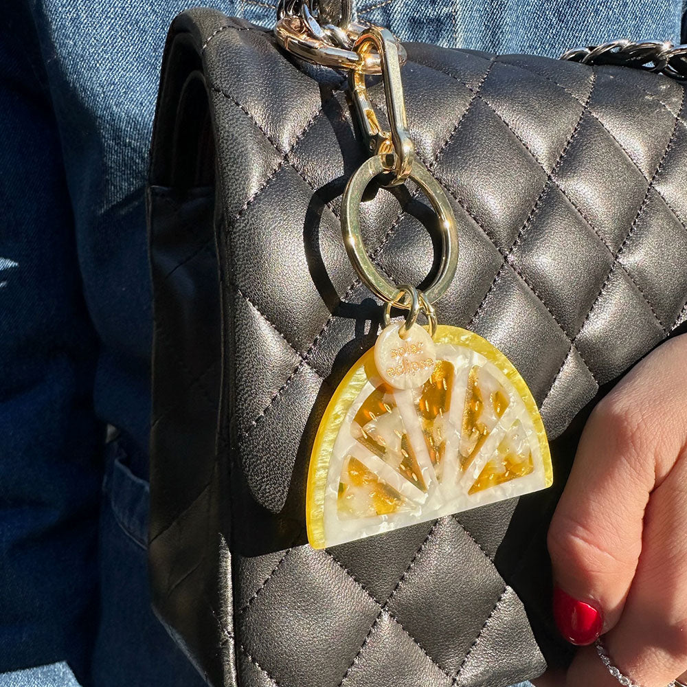yellow lemon slice acetate bag charm on a black quilted handbag