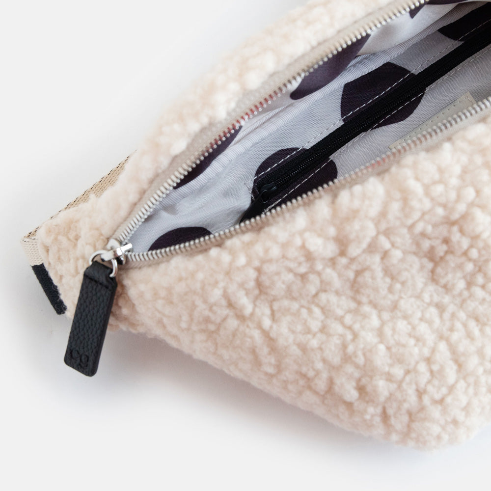 synthetic cream borg crossbody bag with a monochrome strap, black zip pulls and big spots print lining