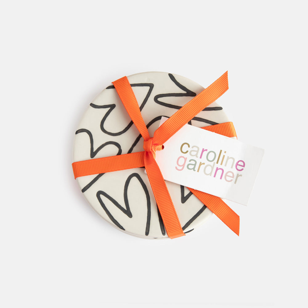 set of four round hand painted ceramic stoneware coasters tied up with a orange ribbon and caroline gardner tag
