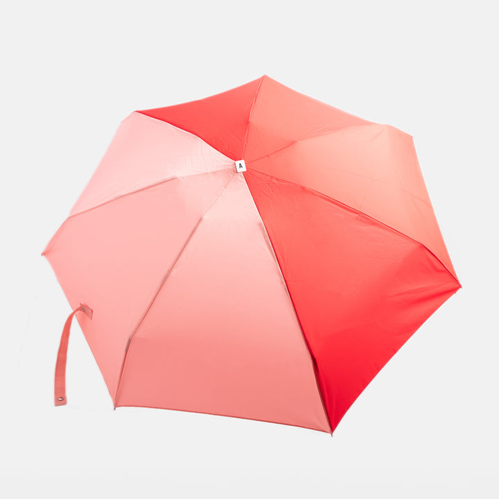 red & pink folding compact umbrella with wooden handle and a monochrome strap