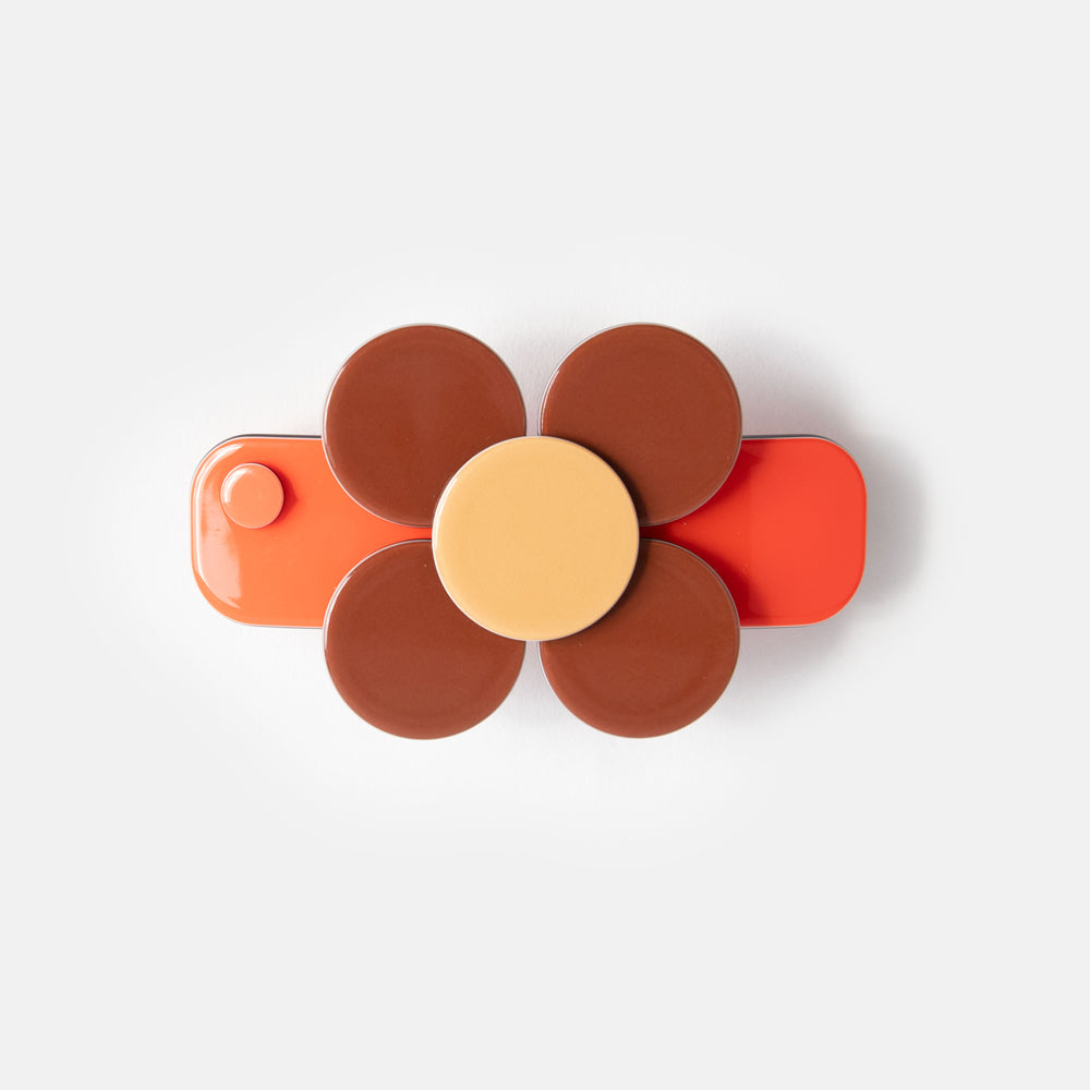 A floral hair clip with orange and brown colors