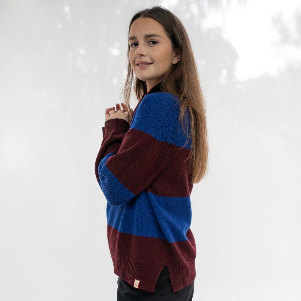 Person wearing a maroon and blue sweater against a white background