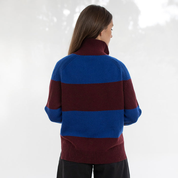 Person wearing a maroon and blue sweater against a white background
