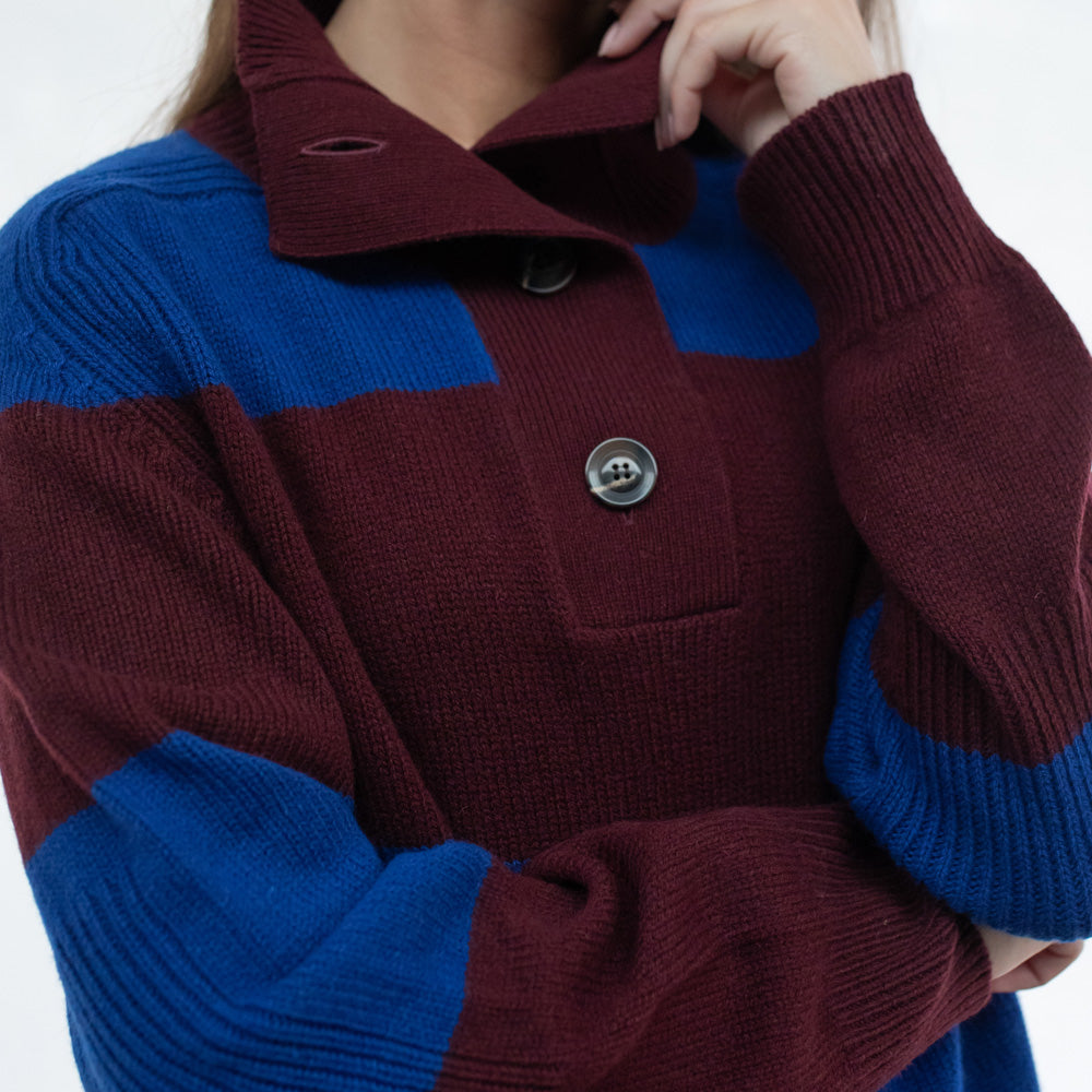 Person wearing a maroon and blue sweater against a white background