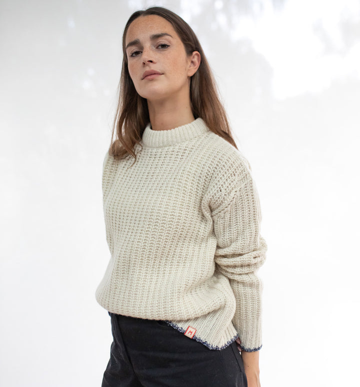 Woman wearing a beige knitted sweater against a white background