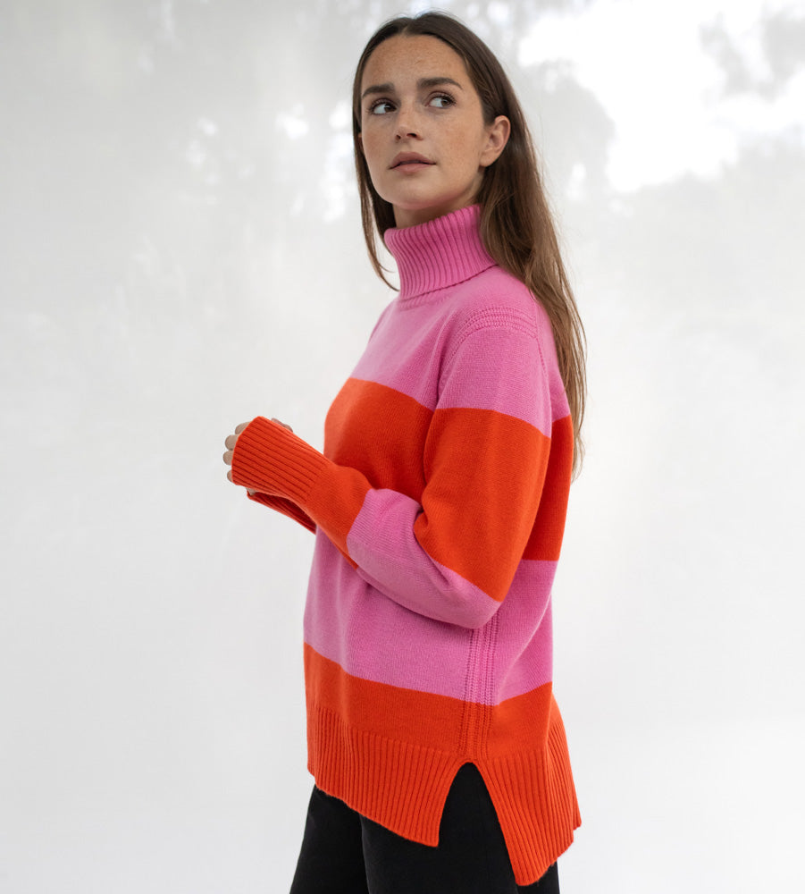 Woman wearing a pink and orange striped sweater against a white background