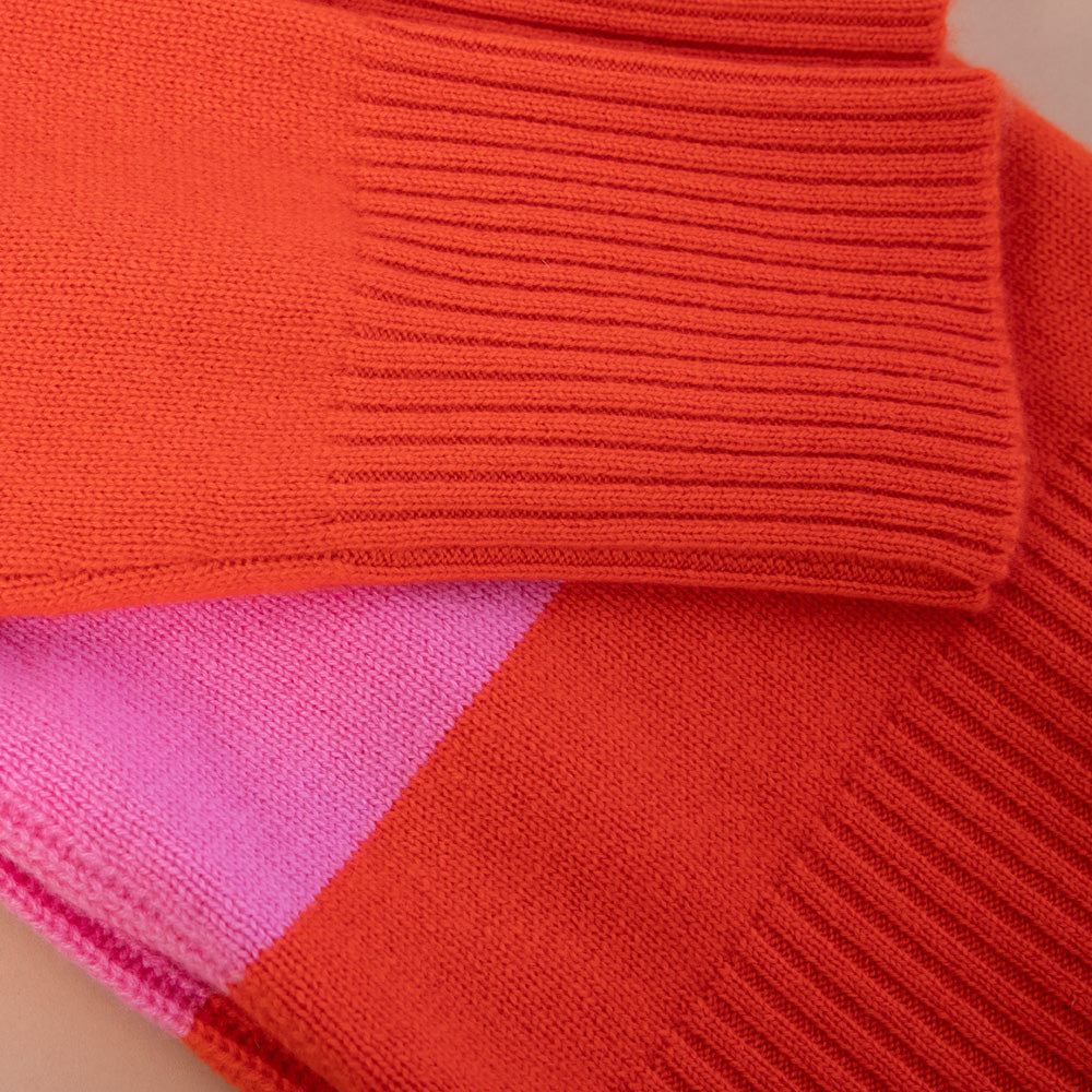 Close-up of a red sweater with a pink patch on a neutral background
