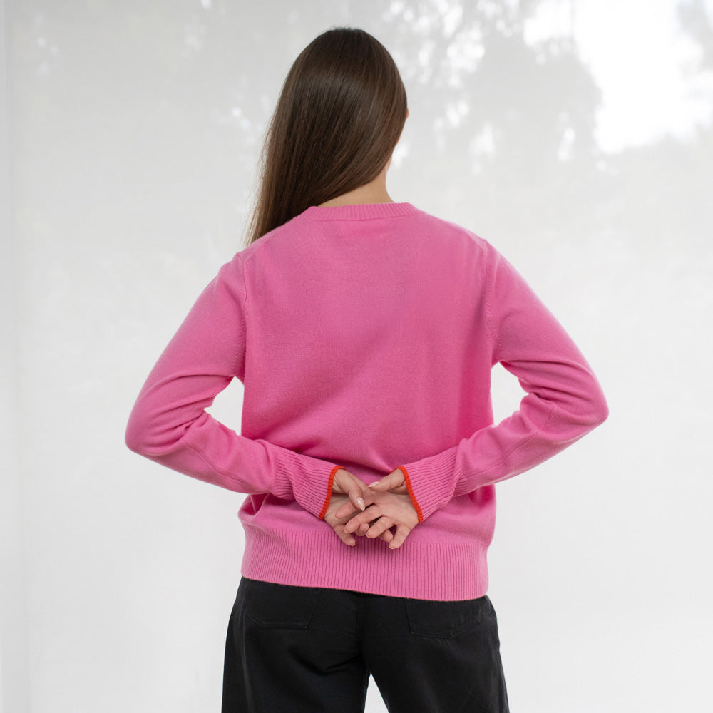 Person wearing a pink sweater with black pants on a white background