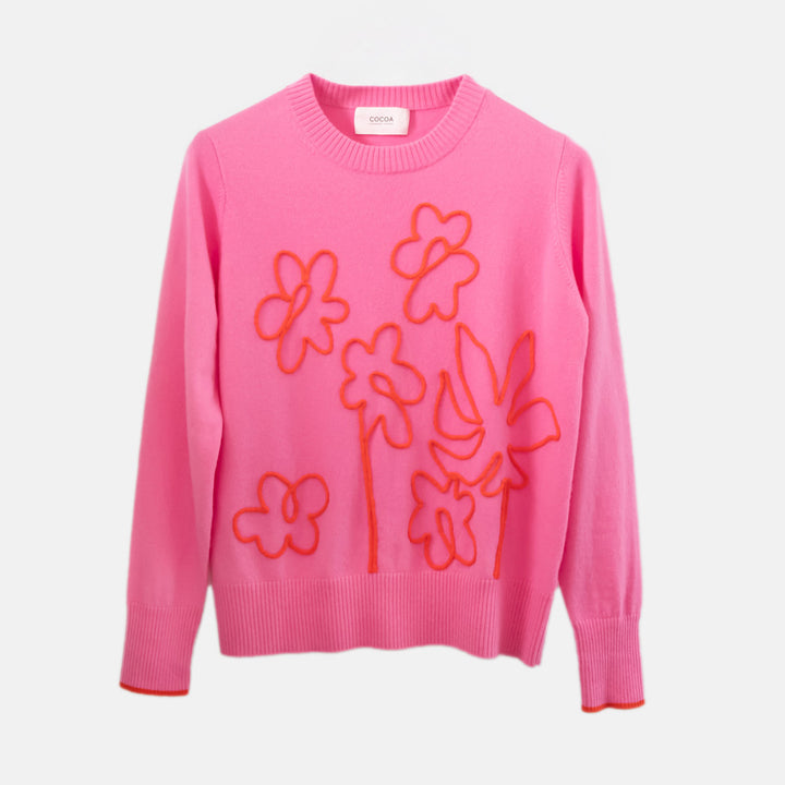 Pink sweater with orange floral patterns on a light gray background