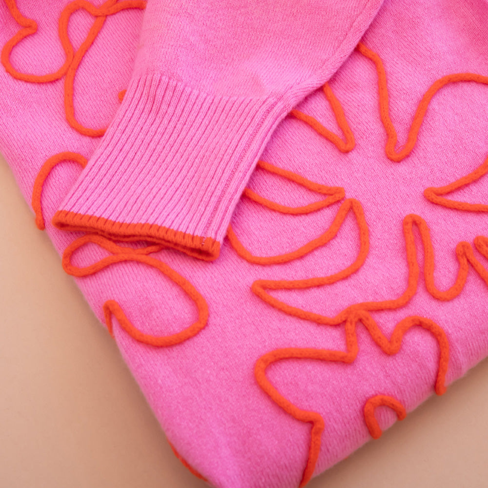 Pink sweater with orange floral patterns on a beige background