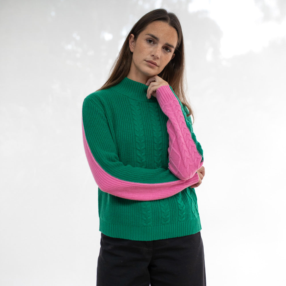 Woman wearing a green and pink sweater against a white background