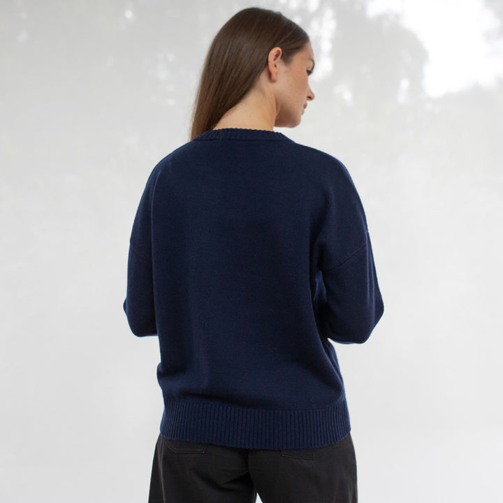Person wearing a navy blue sweater against a white background