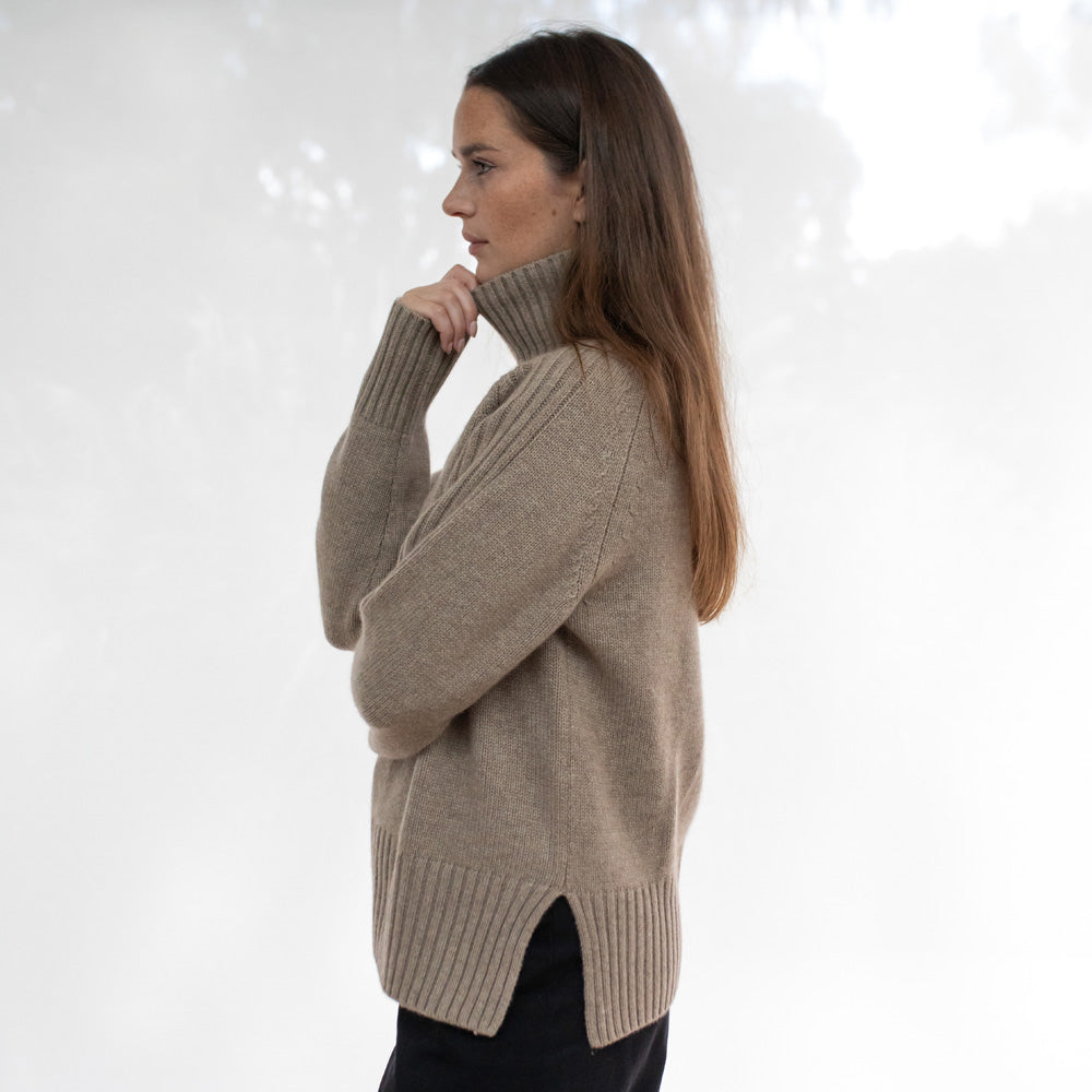 Woman wearing a beige sweater against a white background