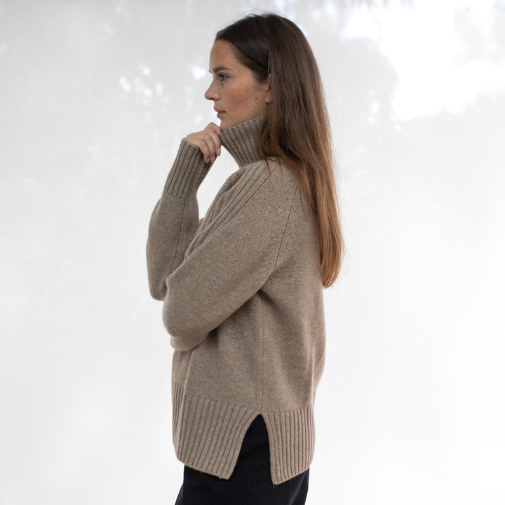 Woman wearing a beige sweater against a white background