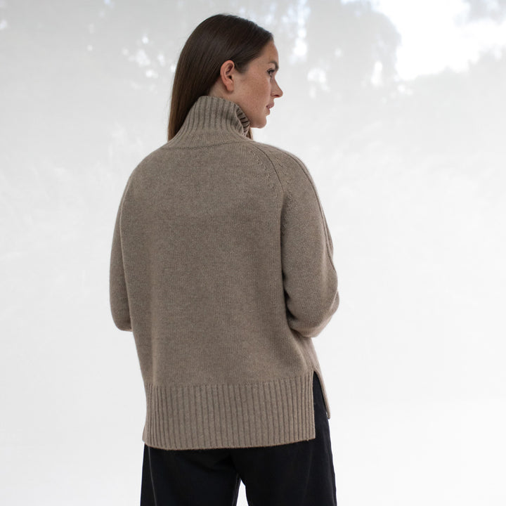 Woman wearing a beige sweater against a white background