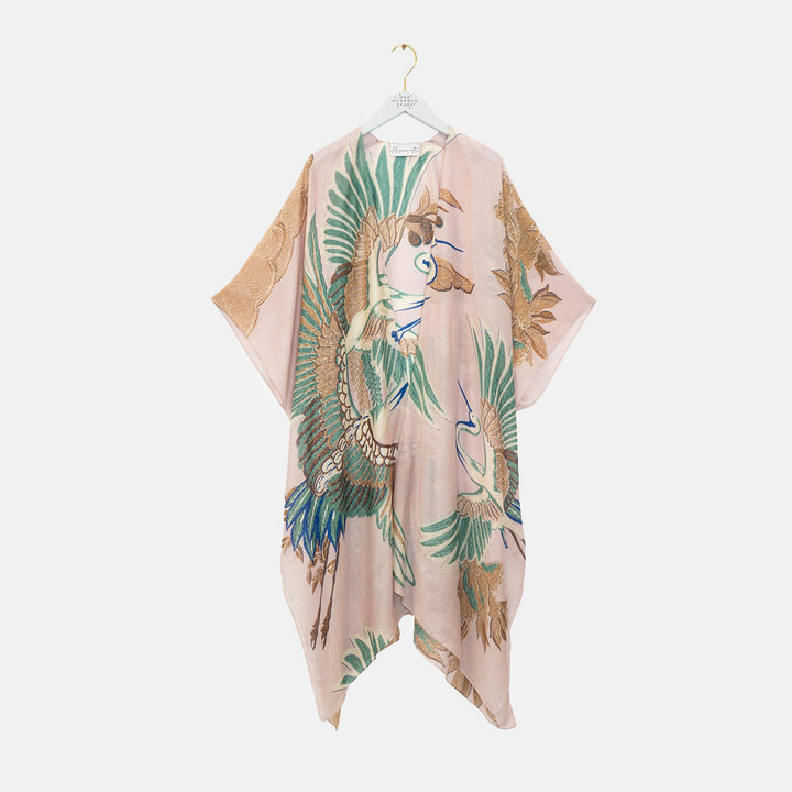 women's throwover top featuring design of cranes in green, brown & blue on a pale pink base