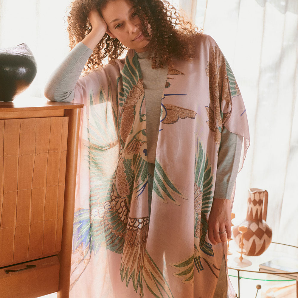 women's throwover top featuring design of cranes in green, brown & blue on a pale pink base