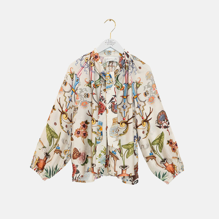 women's tie neck pussy bow shirt blouse featuring print of assorted objec d'art, animals and flowers on an ivory base
