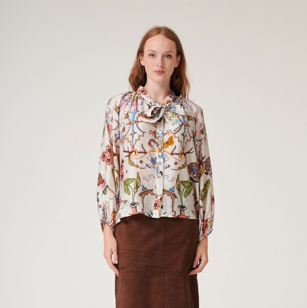women's tie neck pussy bow shirt blouse featuring print of assorted objec d'art, animals and flowers on an ivory base