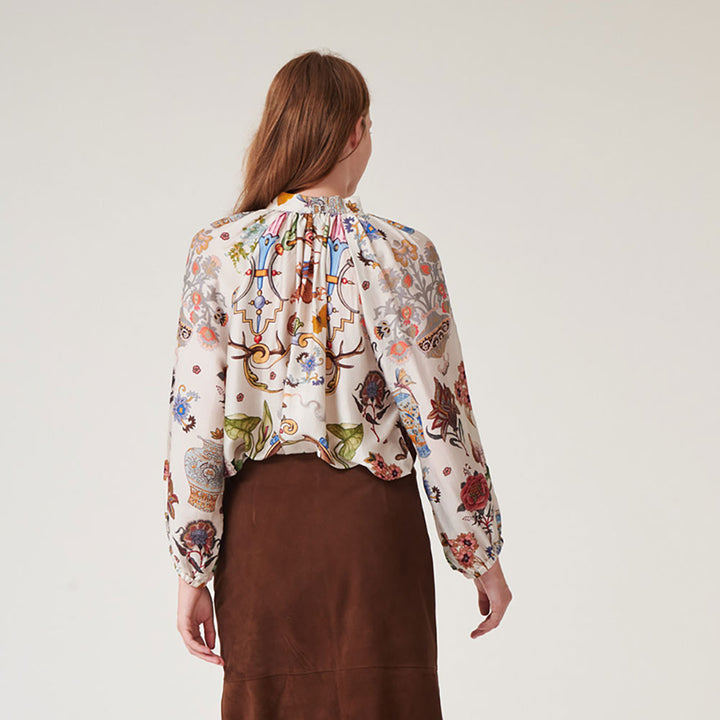women's tie neck pussy bow shirt blouse featuring print of assorted objec d'art, animals and flowers on an ivory base