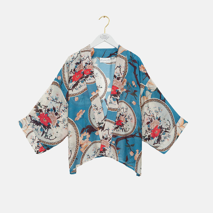 women's short kimono with print of decorative floral plates and white magnolia on a bright blue base