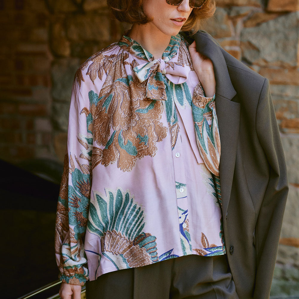 women's tie neck pussy bow shirt blouse featuring print of cranes in green, brown & blue on a pale pink base