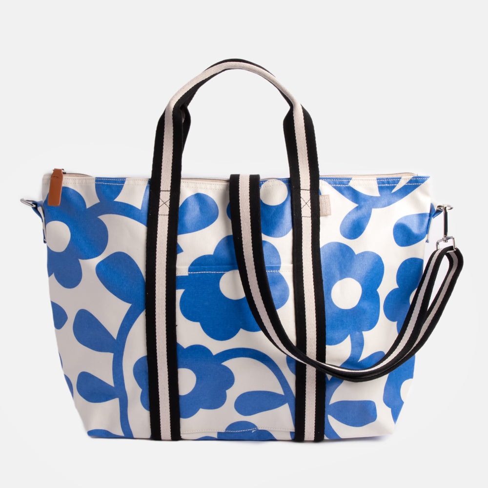 coated cotton canvas weekend bag with blue floral design and monochrome stripe webbing grab handles and detachable shoulder strap