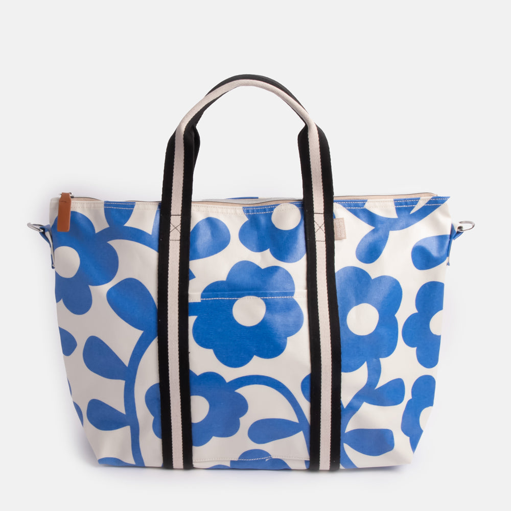 coated cotton canvas weekend bag with blue floral design and monochrome stripe webbing grab handles and detachable shoulder strap