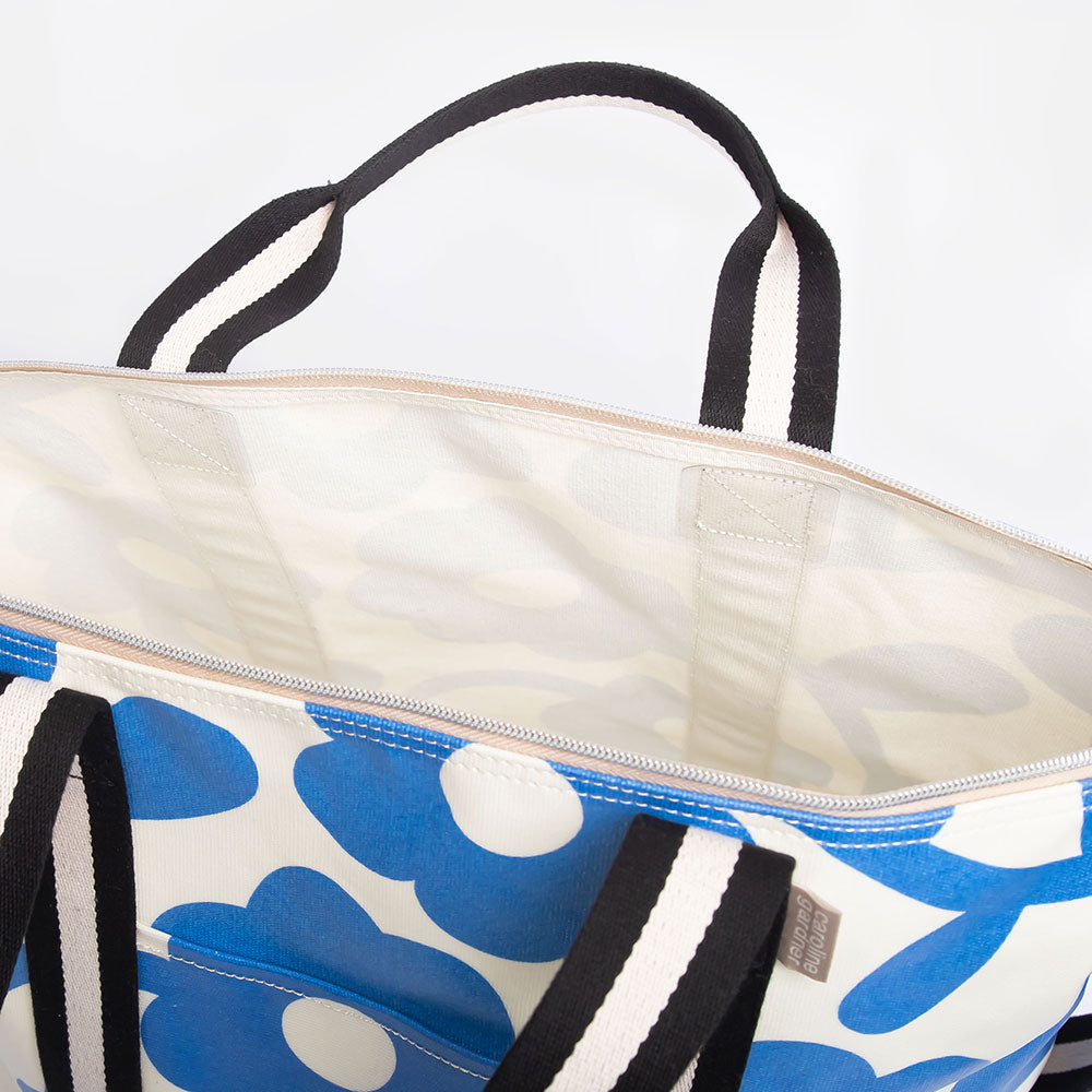 coated cotton canvas weekend bag with blue floral design and monochrome stripe webbing grab handles and detachable shoulder strap