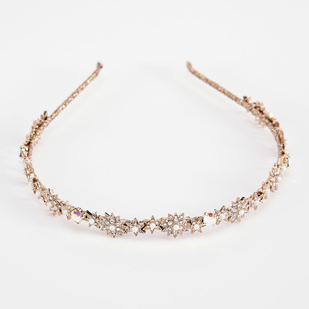 A gold star-shaped headband adorned with crystals and pearls, displayed against a white background