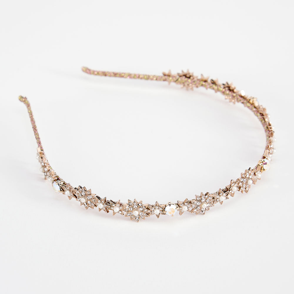 A gold star-shaped headband adorned with crystals and pearls, displayed against a white background