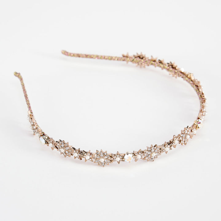 A gold star-shaped headband adorned with crystals and pearls, displayed against a white background