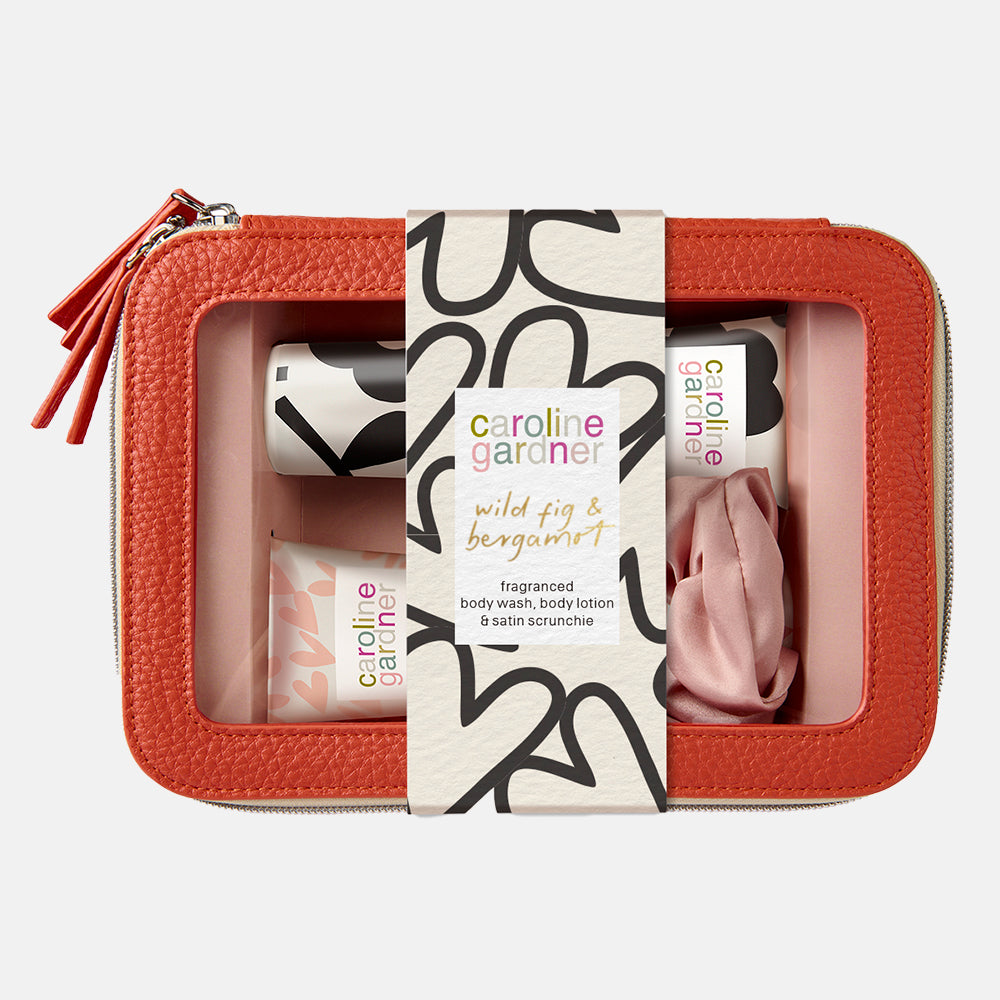 caroline gardner orange wash bag gift set containing wild fig & bergamot body lotion & body wash and a pink scrunchy. 