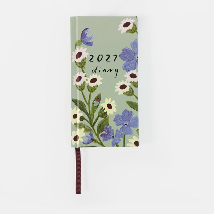 A 2027 daily planner with a sage green cover decorated with blue and white wildflowers, featuring a dark brown ribbon bookmark.