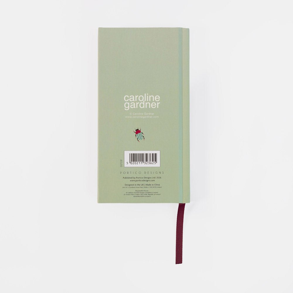 A light sage green notebook with a burgundy ribbon bookmark, featuring the text 'caroline gardner' and a small red flower illustration on the back cover, set against a plain white background.
