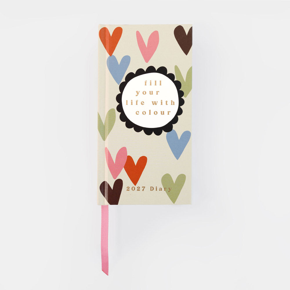 A 2027 daily planner with a cream-colored cover decorated with colorful hearts in orange, pink, blue, brown, and green. The center features a white oval with the text 'fill your life with colour' inside a black scalloped circle.