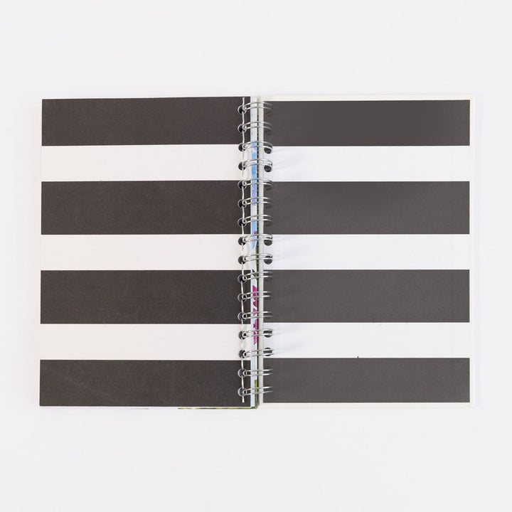 A spiral-bound notebook with a black and white striped cover, shown open against a plain white background.