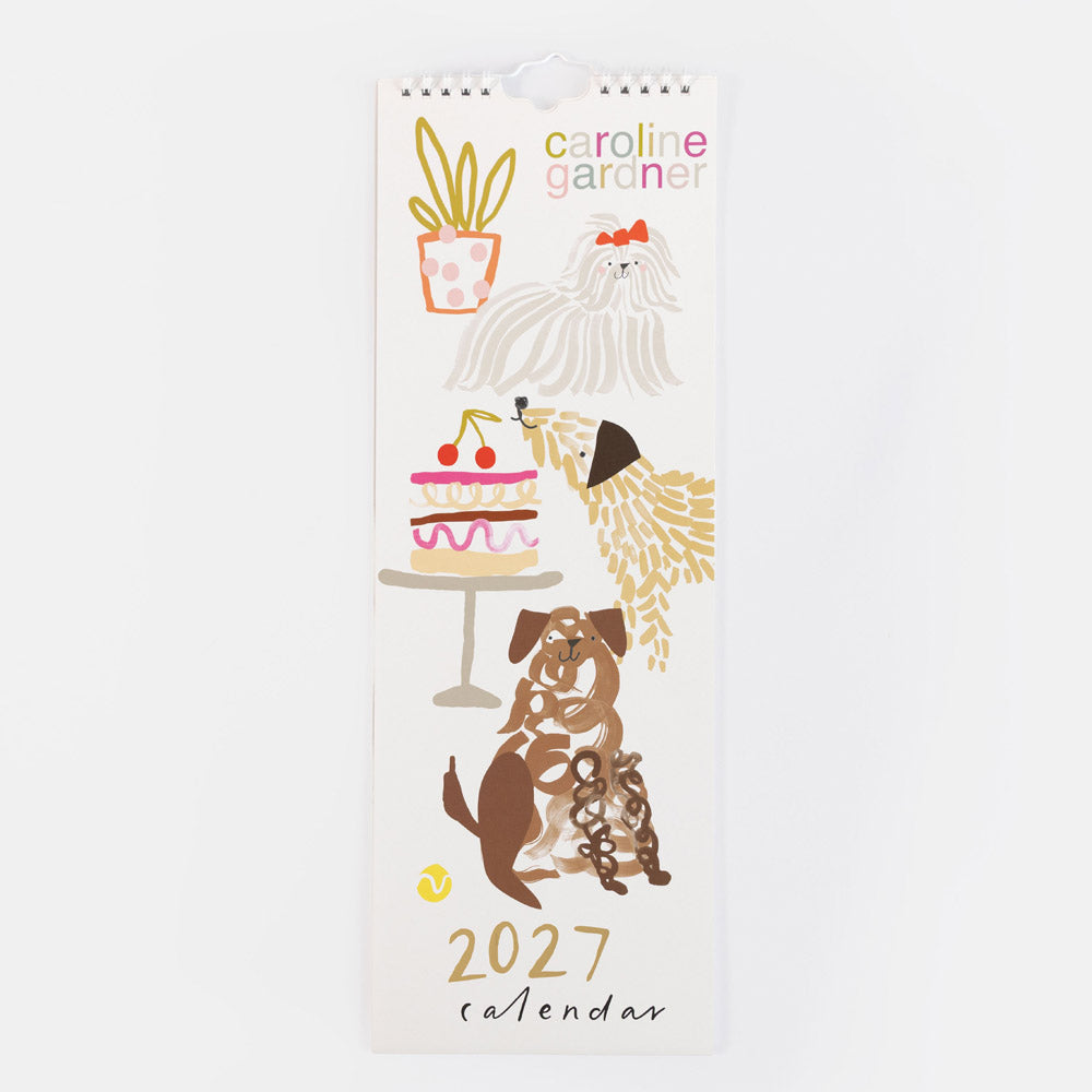 A vertical 2027 wall calendar by Caroline Gardner featuring whimsical dog illustrations and small doodles, photographed against a plain white background.