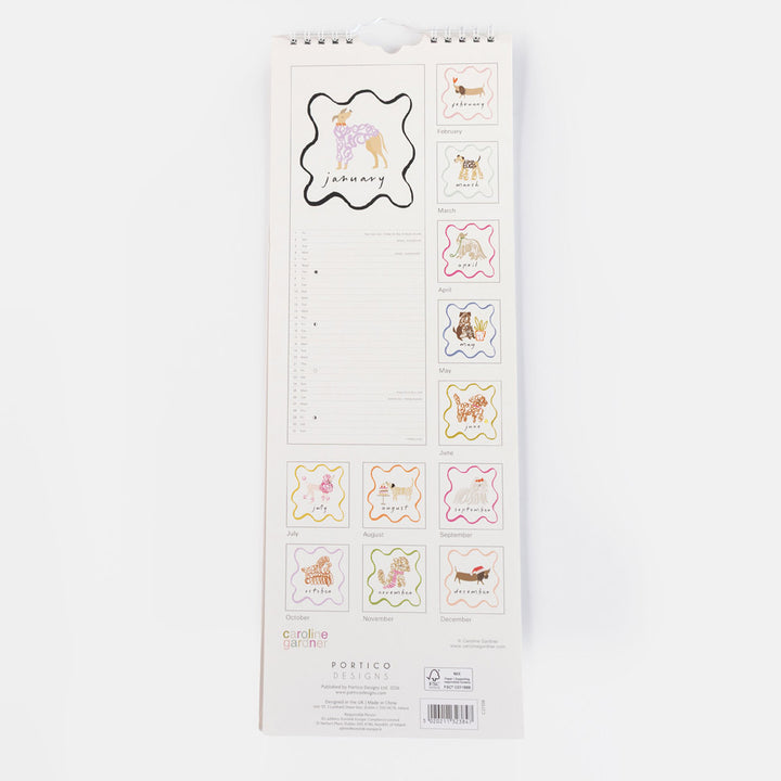 A vertical hanging paper calendar page with lined daily writing space and small decorative dog-themed label stickers shown along the right side. The page has a white background and visible printed branding near the bottom reading Colorful Calendars and Portico.