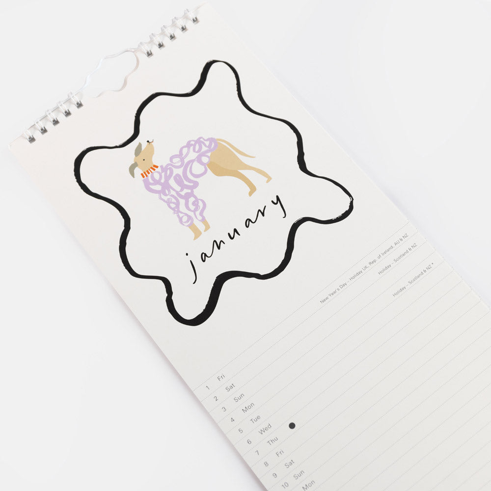 A spiral-bound January calendar page with a decorative black outline badge showing a dog illustration and the word 'january' in script, photographed on a clean white background.