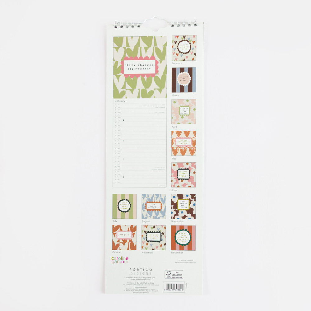 A vertical spiral-bound calendar page set from Portico Designs, featuring various decorative labels, stickers, and a lined writing sheet on a white backing card, photographed against a plain white background.