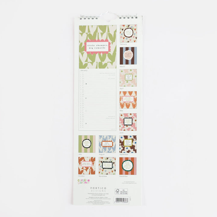 A vertical spiral-bound calendar page set from Portico Designs, featuring various decorative labels, stickers, and a lined writing sheet on a white backing card, photographed against a plain white background.