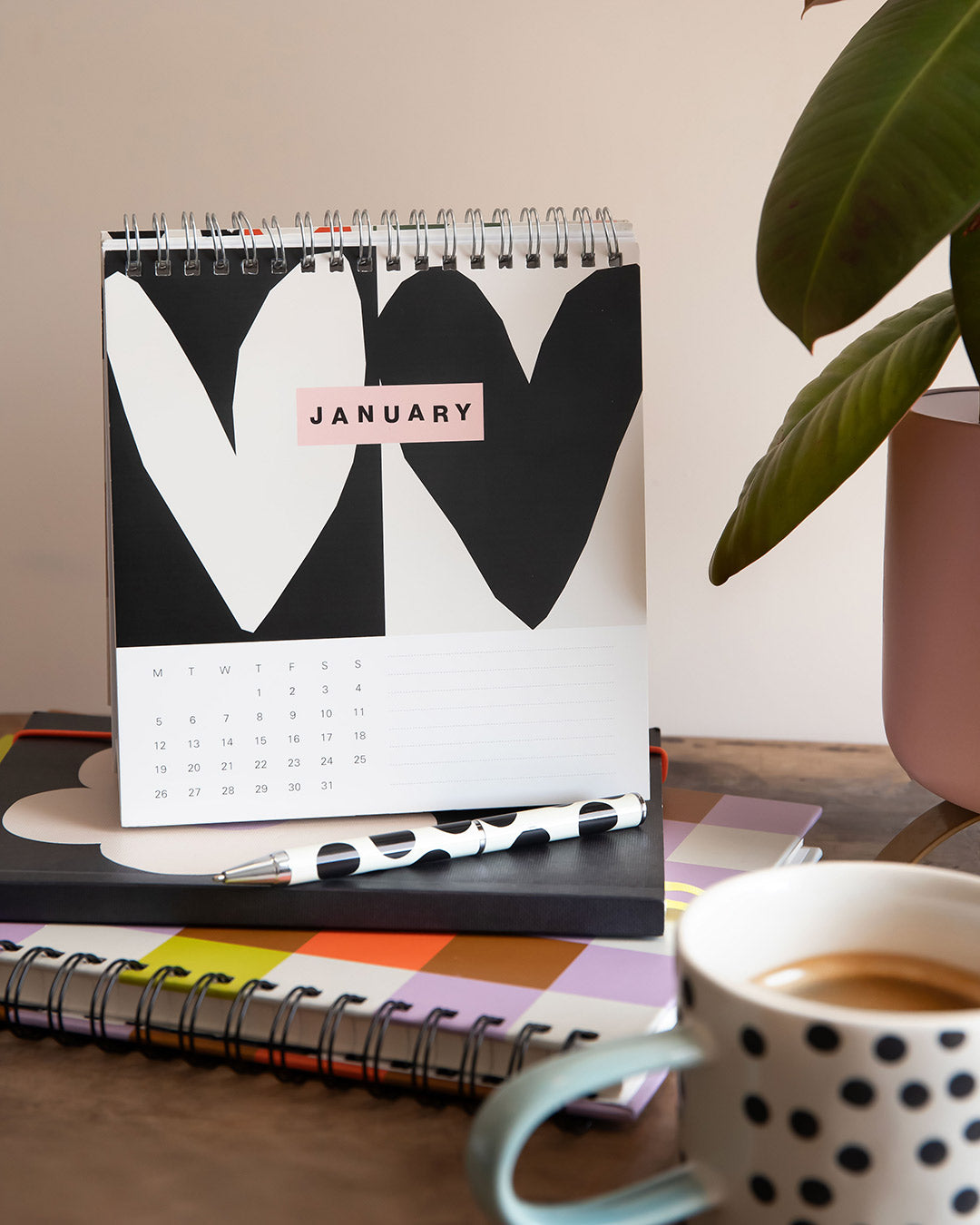 Calendar with a heart design on a desk with a cup of coffee and a pen.