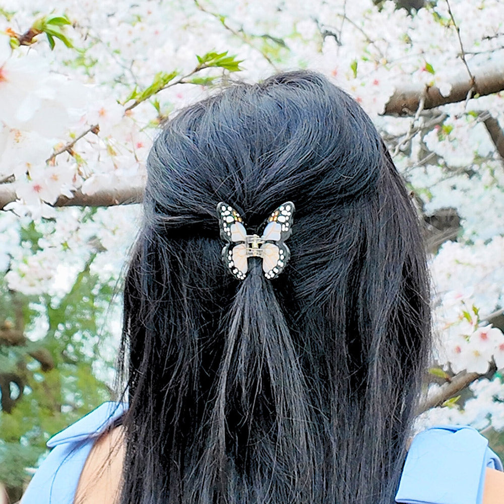 Person with black hair featuring a butterfly hair clip against a floral background