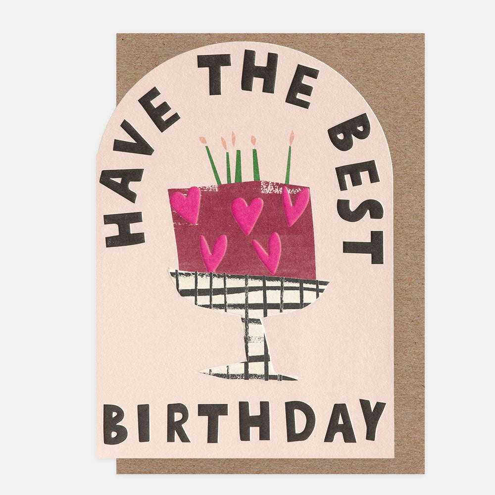 birthday card with a curved top featuring a hand drawn cake on a stand with pink love hearts on and the words 'have the best birthday'