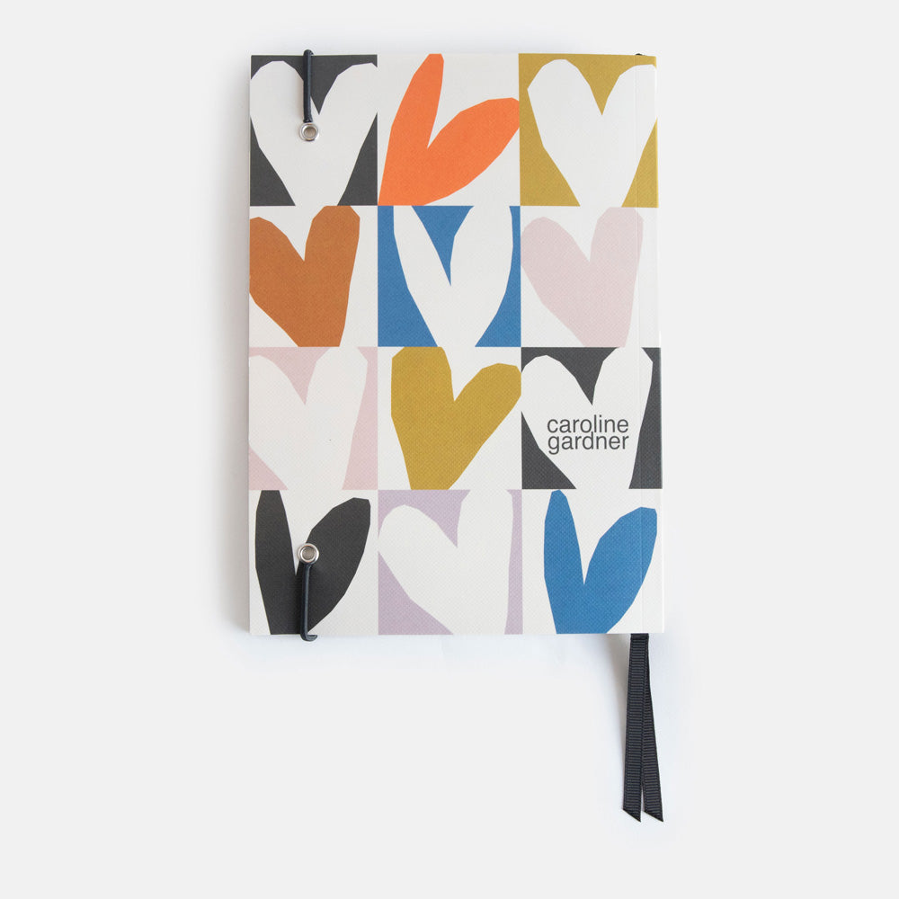 A5 softcover notebook with a multicolour hearts print, black ribbon page markers and elastic band