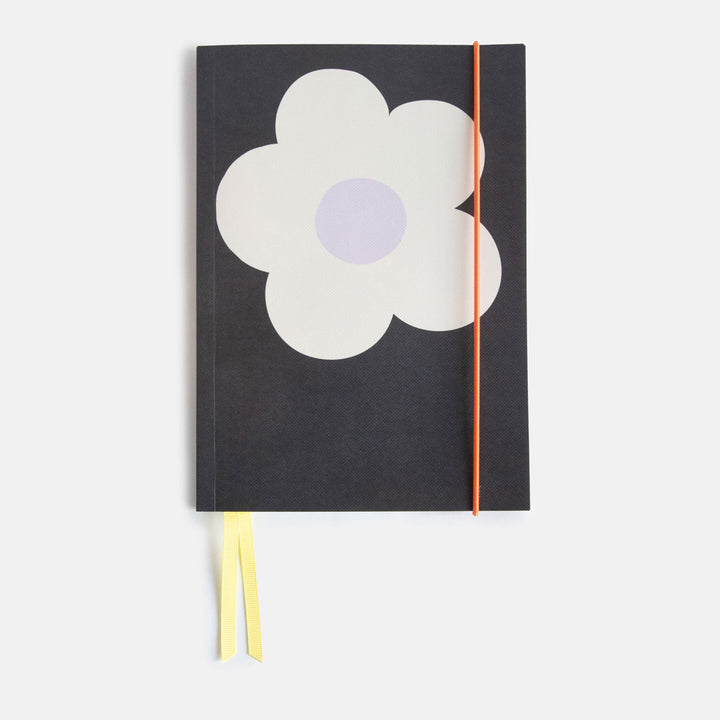 A5 softback notebook with a big cream flower on a charcoal background design, yellow ribbon page markers and orange elastic band