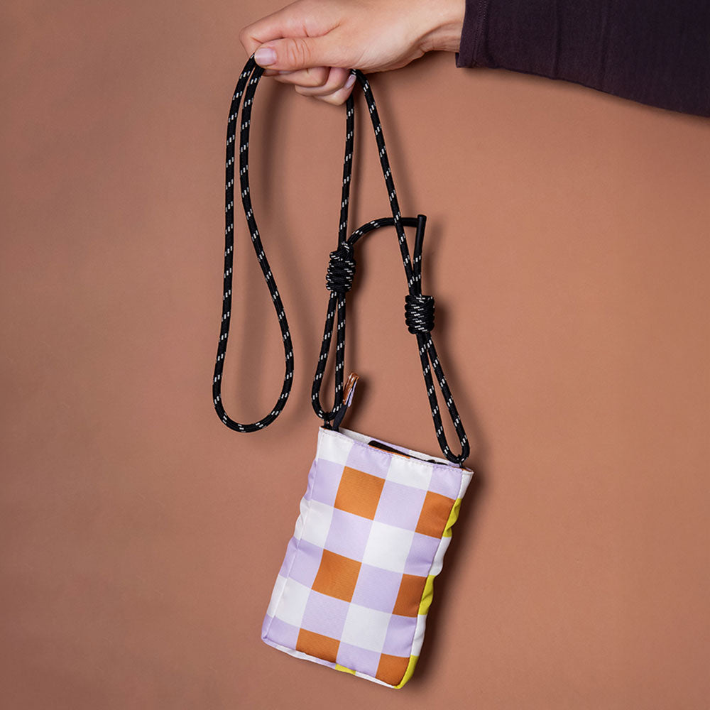 nylon padded phone bag in warm tones check design, with a monochrome adjustable cord strap and black zip pull