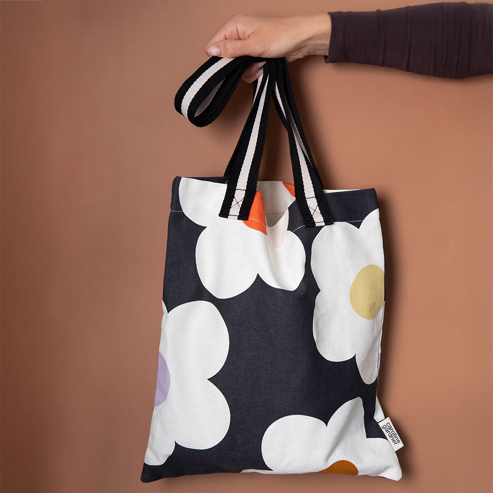 hand printed cotton canvas tote bag with colourful flowers on charcoal design and monochrome stripe webbing handles